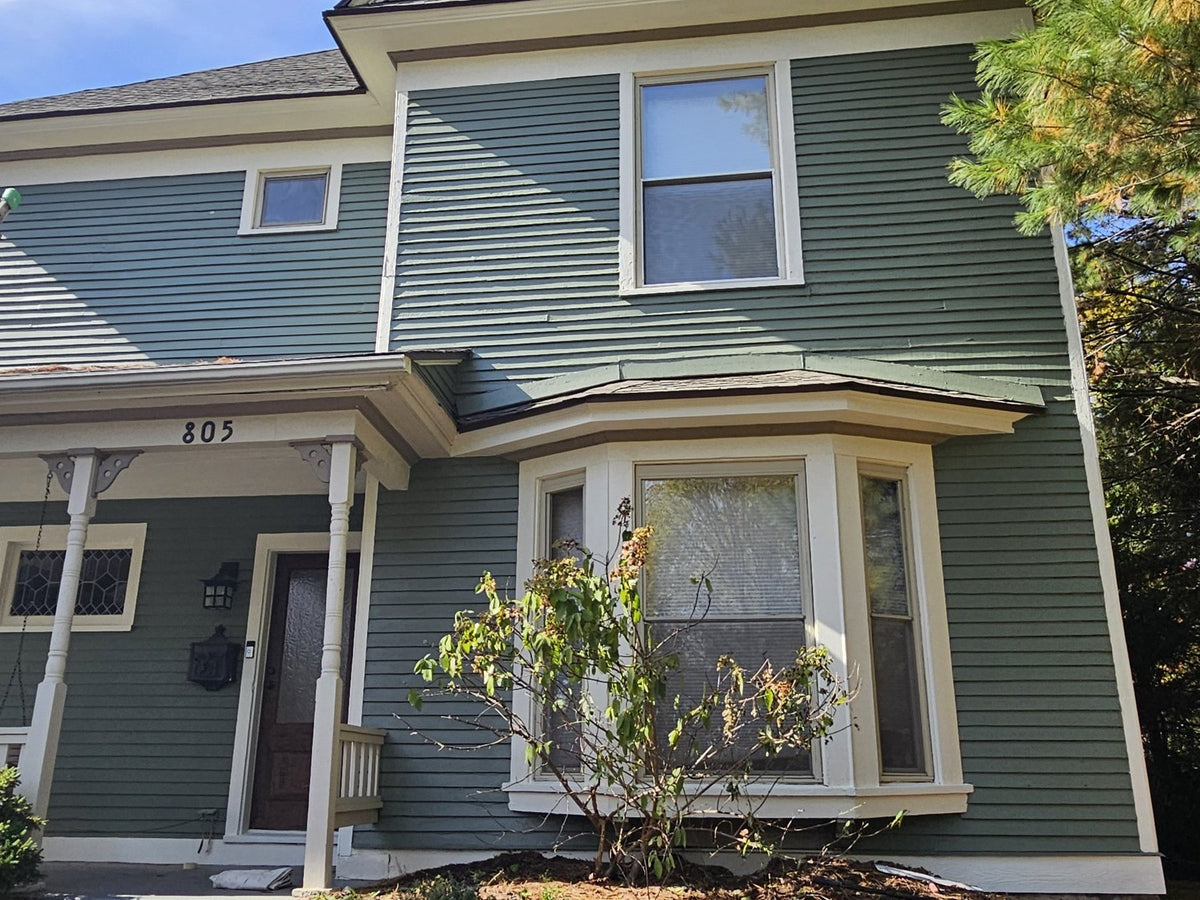 Green two-story house after an exterior repaint by Cardinal Painting Services